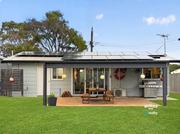 This modern home features a spacious outdoor area with solar panels and a built-in grill for entertaining.