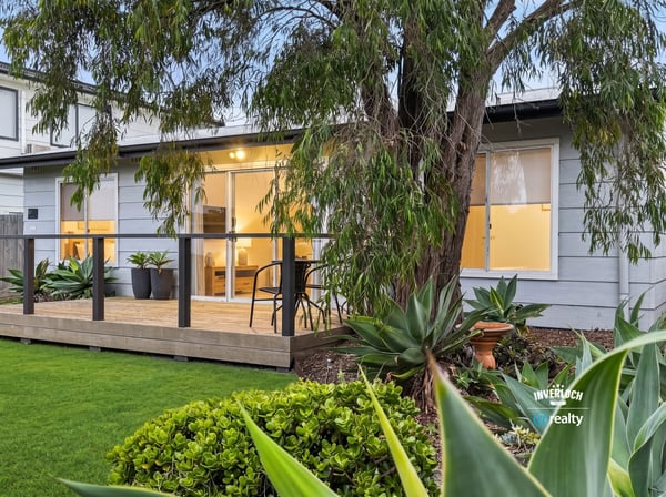 Bright and inviting home featuring a spacious deck, lush landscaping, and modern living spaces.