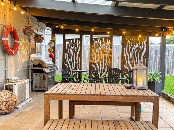 Discover an inviting outdoor space featuring a cozy dining area, grill, and decorative privacy screens.