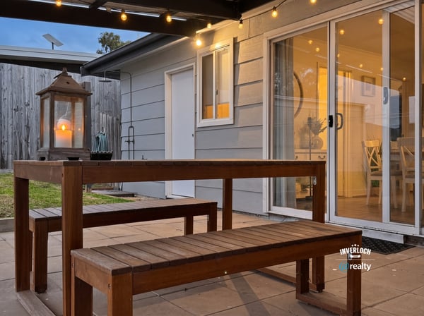 This inviting outdoor space features a wooden dining set and soft lighting, perfect for gatherings.