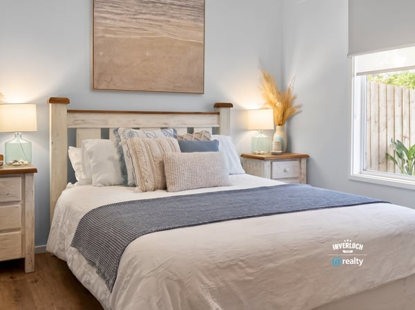 Bright and inviting bedroom features coastal decor, cozy bedding, and natural light streaming through the window.