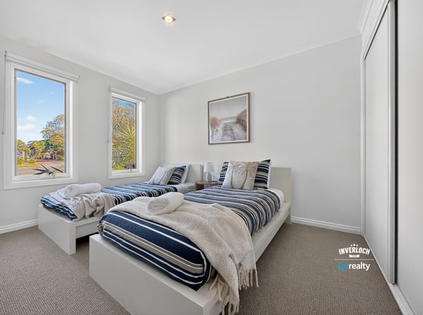 Bright and inviting bedroom with ample natural light, featuring twin beds and modern aesthetics.