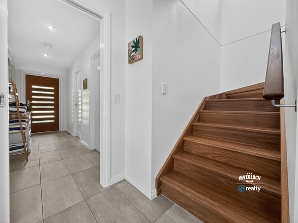 Modern entryway featuring open space, inviting natural light, and a warm wooden staircase.