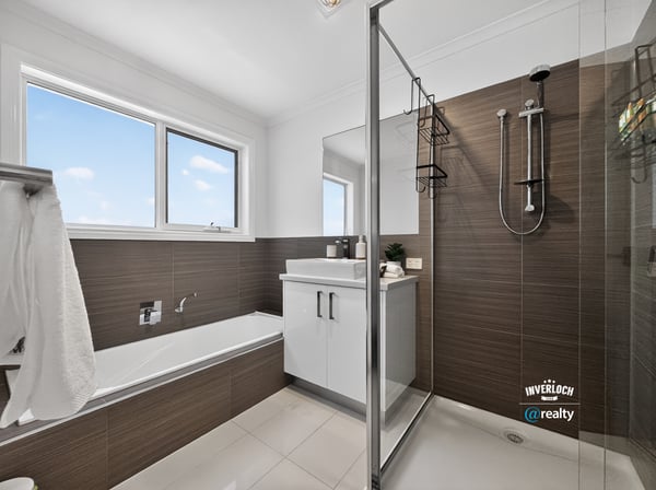Modern bathroom featuring a glass shower, freestanding tub, and ample natural light from large windows.