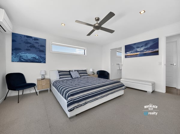 Light-filled bedroom featuring modern decor, ample space, and beautiful ocean-themed artwork for a refreshing atmosphere.