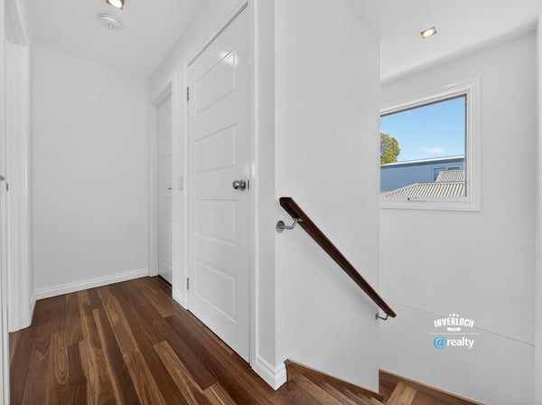 Bright and inviting hallway featuring warm wood flooring and ample natural light from the window.