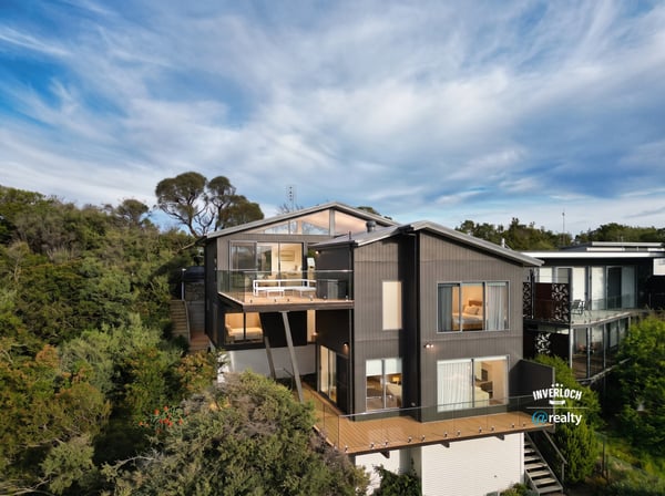 Contemporary home nestled in nature, featuring expansive decks and large windows that invite abundant natural light.