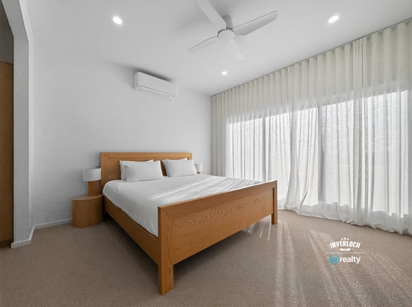 Bright and airy bedroom featuring large windows, modern furnishings, and ample natural light.