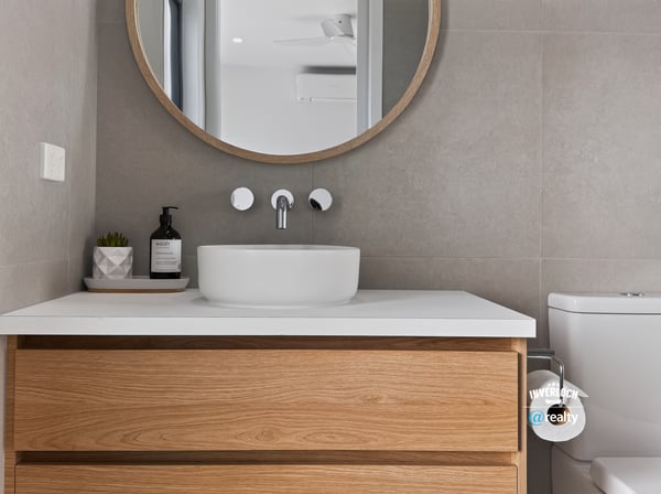 Modern bathroom featuring a sleek sink, circular mirror, and warm wooden cabinetry for practical elegance.