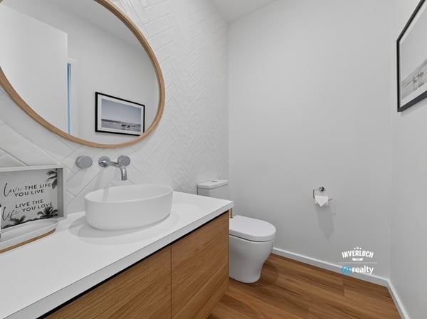 Bright and modern bathroom featuring a unique round mirror and sleek wood cabinetry for functional appeal.