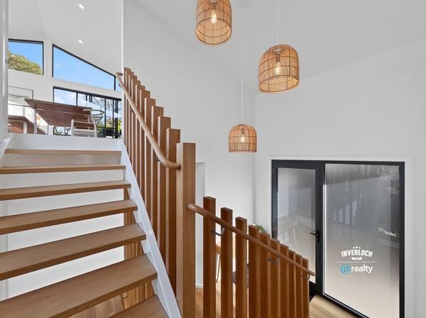 Bright and airy entryway featuring modern lighting and open staircase, seamlessly connecting indoor and outdoor spaces.