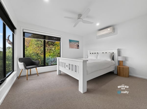 Bright bedroom with large windows showcasing natural light and leafy views, featuring modern finishes and comfort.