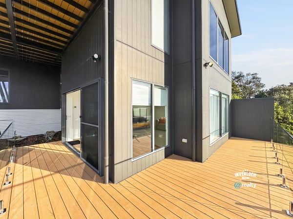 Modern home featuring a spacious outdoor deck and large windows, perfect for entertaining and natural light.