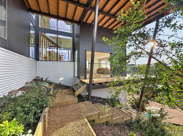 Contemporary home featuring expansive windows, a spacious deck, and beautifully landscaped outdoor areas for relaxation.