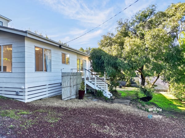 This inviting home features a spacious yard and a welcoming entrance surrounded by lush greenery.