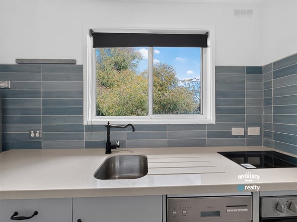 Modern kitchen featuring sleek countertops and a large window that offers refreshing garden views.
