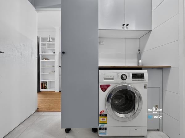 Compact laundry area featuring modern appliances and efficient storage solutions for optimal functionality.