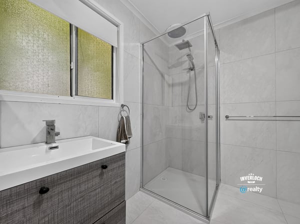 Modern bathroom featuring a walk-in shower and sleek cabinetry, designed for functionality and comfort.
