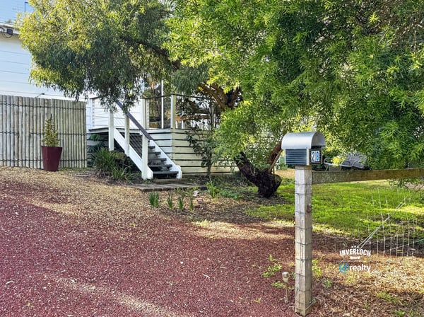 This property features a spacious yard with mature trees and a welcoming front porch, ideal for gatherings.