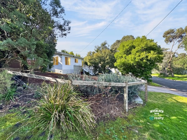 Quaint home nestled among lush greenery, featuring a spacious yard and a peaceful neighborhood setting.