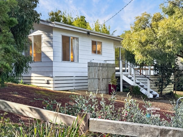 This inviting home features ample windows, a spacious outdoor area, and a welcoming front porch.