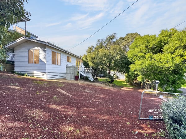Bright, inviting home on a hillside lot, featuring expansive outdoor space and potential for personalization.