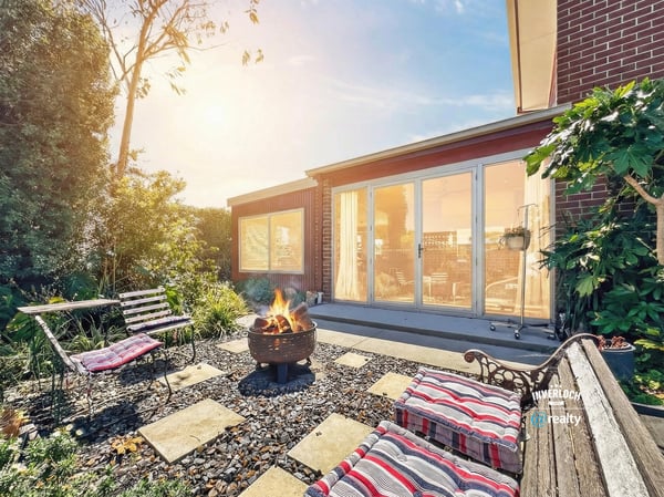 Enjoy outdoor gatherings in this inviting backyard, complete with a cozy fire pit and lush greenery.