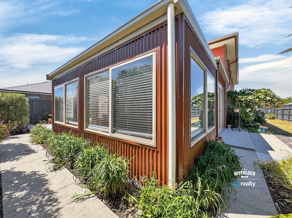 This contemporary home features expansive windows, inviting natural light and showcasing the surrounding greenery.