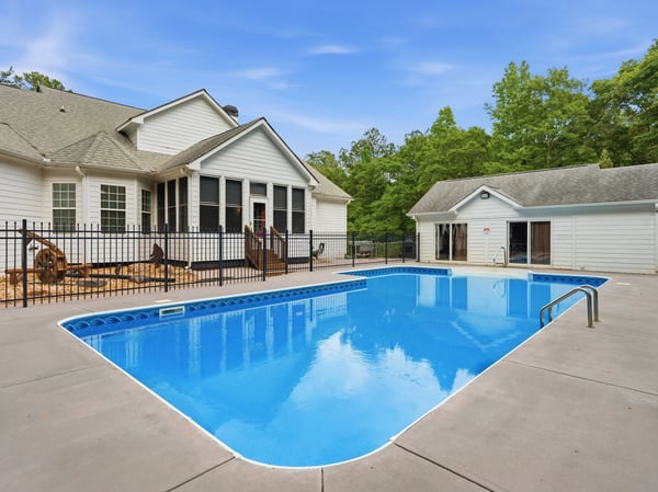 This spacious property features a generously sized pool surrounded by a fenced patio, perfect for outdoor gatherings.