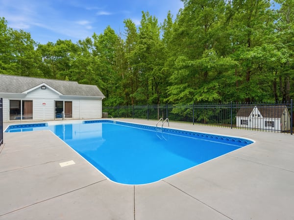 Discover this inviting backyard oasis featuring a spacious pool and a private poolhouse, surrounded by lush greenery.