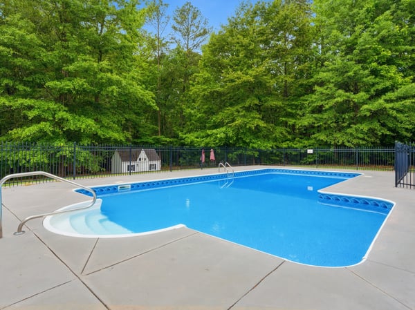 Discover a private oasis featuring a spacious pool surrounded by lush greenery, perfect for outdoor relaxation.