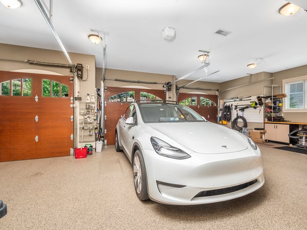 Spacious garage featuring ample storage, three doors, and modern finishes, perfect for vehicle and equipment maintenance. EV charging stations. Most walls are slatwalls. There is ample cabinetry and a closet. The room is both heated and cooled.