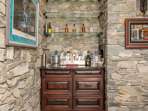 Discover a unique bar area featuring stone walls and custom shelving, perfect for entertaining guests.