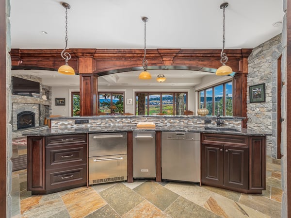 The full bar/wine cellar incorporates a modern kitchen with stone accents, expansive views, and high-end appliances, perfect for entertaining and gatherings.