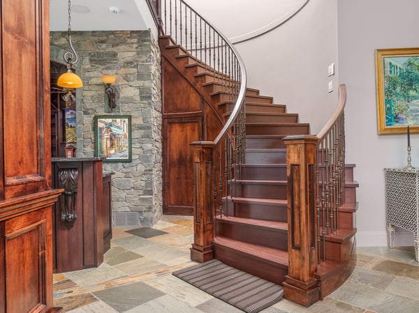 Discover a stunning entryway, as seen from the lower floor, featuring a grand spiral staircase, rich wood accents, and masterful wood craftsmanship.