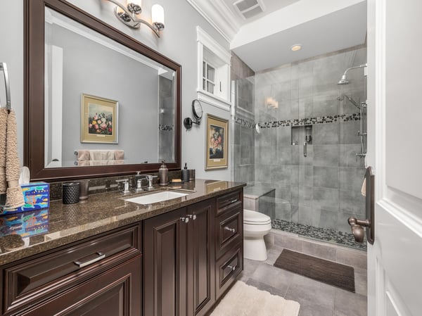 This well-appointed ensuite bathroom features granite countertops, modern fixtures, and a spacious glass-enclosed shower.