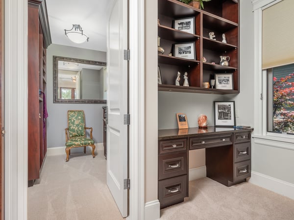 Bright home office in the guest bedroom, featuring custom shelving, natural light, and a cozy seating area for productivity.