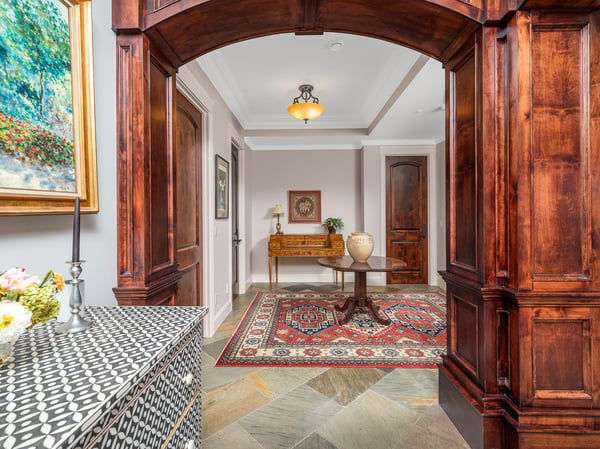 The welcoming transition from the grand room to the bedrooms' entrances and half bathroom features distinctive woodwork and artistic decor.