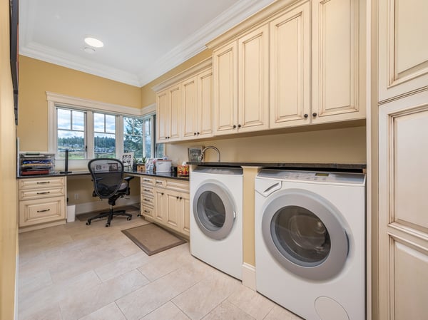 Bright laundry room featuring spacious cabinetry, a dedicated workspace, and large windows for natural light.