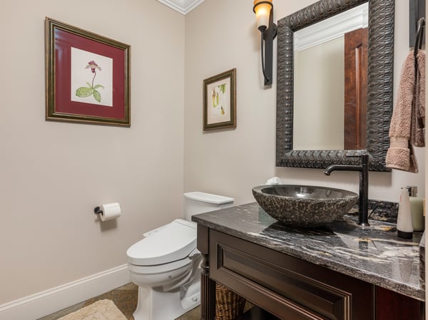 Modern bathroom featuring a unique underlit vessel sink, artistic decor, and a warm, inviting atmosphere.