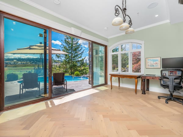 Bright and airy room featuring large windows, beautiful hardwood floors, and stunning poolside views.