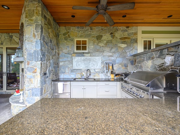 Experience outdoor cooking in this inviting stone-clad kitchen with modern appliances and spacious countertop areas.