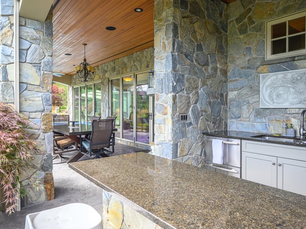 This outdoor space features a spacious stone patio with a built-in bar and comfortable seating.