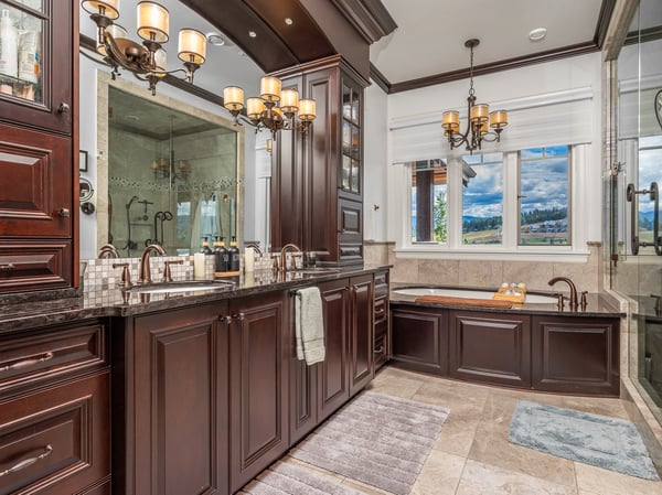 Luxurious bathroom featuring dark wood cabinetry, modern fixtures, and a spacious soaking tub with scenic views.