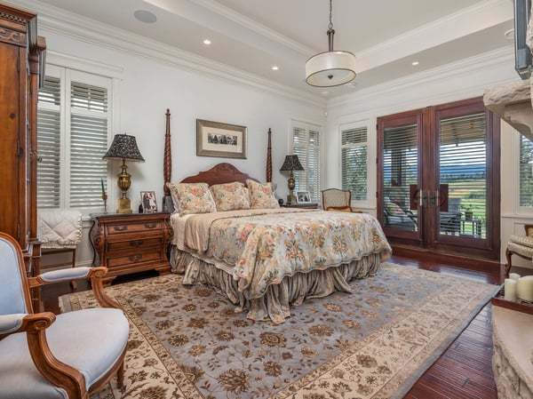 Spacious primary bedroom featuring rich textures, large windows, and a cozy seating area with scenic views.