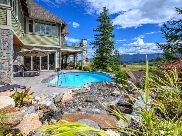Stunning hillside home featuring a vibrant pool and sweeping views of the surrounding landscape.
