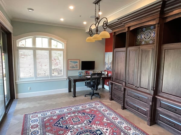 Spacious office featuring custom cabinetry, large windows for natural light, and a decorative area rug.