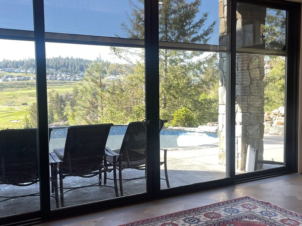Inviting space features floor-to-ceiling windows showcasing expansive views of lush landscapes and outdoor relaxation areas.