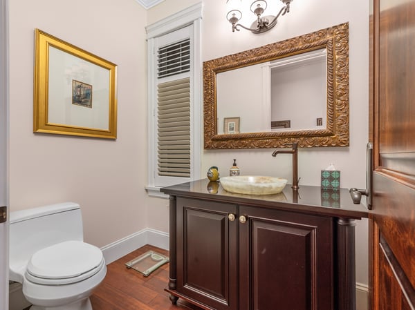 This inviting bathroom features a sleek vanity, distinctive mirror, and warm wood accents throughout.