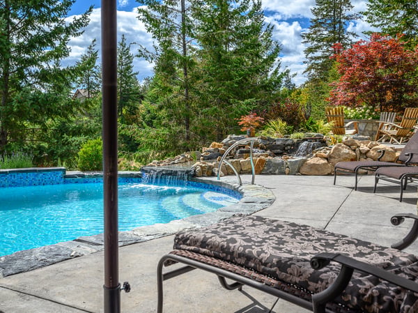 Relax by the inviting pool surrounded by lush landscaping and vibrant greenery, perfect for outdoor enjoyment.